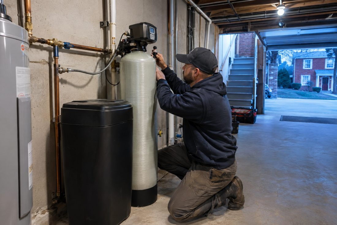 A water softener being connected in a garage at a red-brick Cincinnati home with a basement in Cincinnati, OH